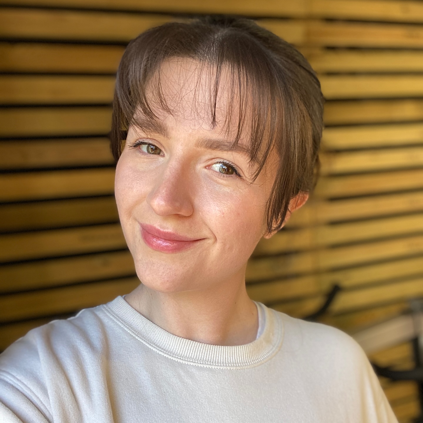 Robyn Anderton smiling, in front of a mustard slat wall